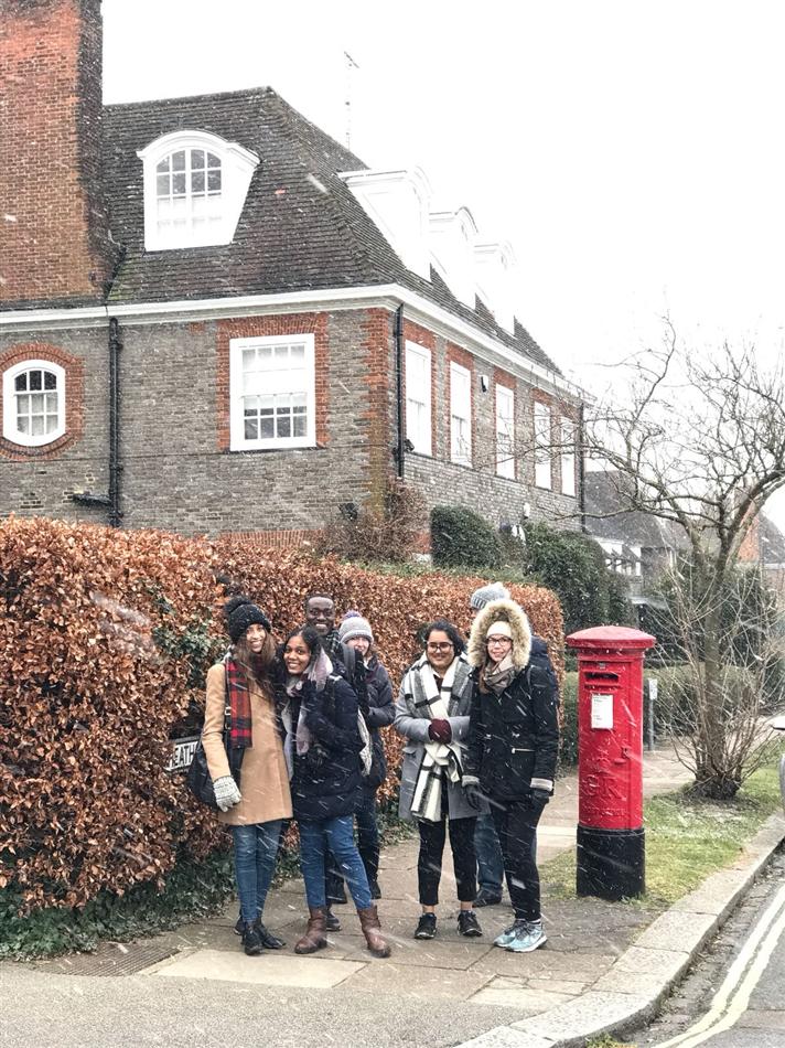 Friends in the snow beside a red London postbox