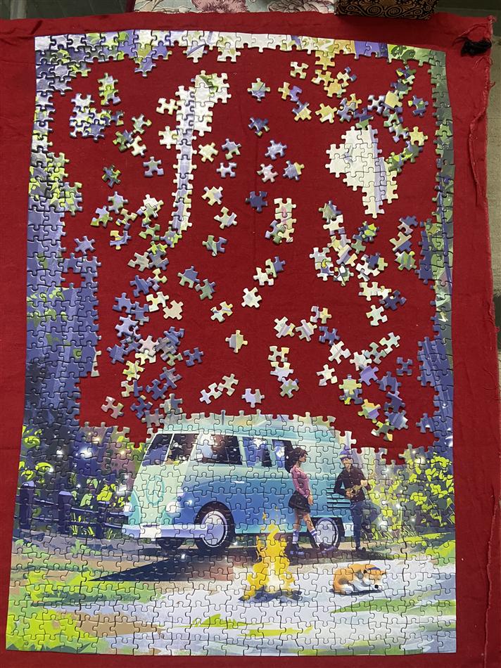 A half-finished jigsaw puzzle of a car by a lake